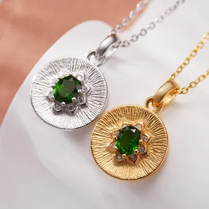 Detailed view of silver and gold necklaces with oval green diopside gemstone pendants.