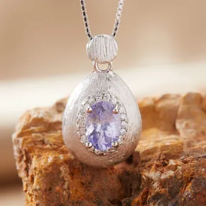 Macro detail of silver amethyst necklace with brushed finish on natural rock background