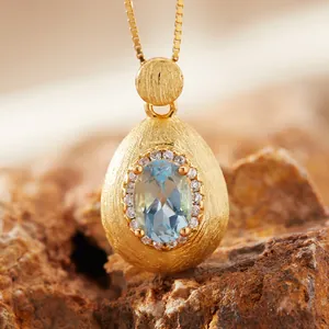 Macro view of a blue gemstone pendant with a brushed gold finish and stone accents