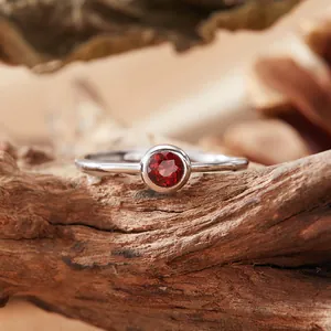 Close-up of a S925 silver ring featuring a round natural garnet on a wood background