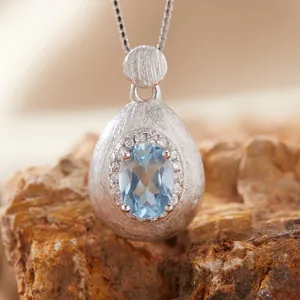 Macro view of brushed S925 silver teardrop pendant with light blue gemstone and small crystals