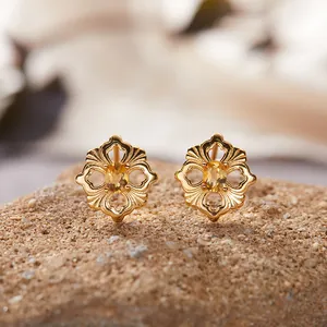 Nahaufnahme von goldenen Vintage-Ohrringen mit hohlem Blumenmuster und gelbem Edelstein im Fokus