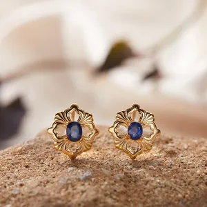 Nahaufnahme goldener Ohrringe im Vintage-Blumendesign mit blauen Edelsteinen auf Steinoberfläche