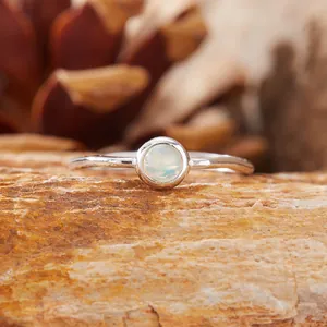 Primo piano di un anello d'argento con opale rotondo su pietra naturale