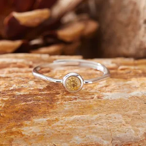 Elegante anello in argento S925 con citrino rotondo su una superficie di roccia naturale