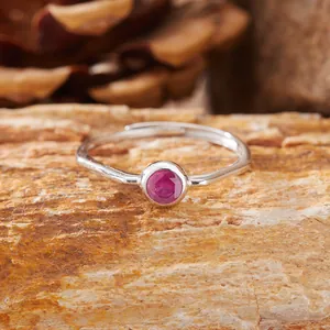 Dettaglio di un anello d'argento con ametista su sfondo di pietra naturale grezza.