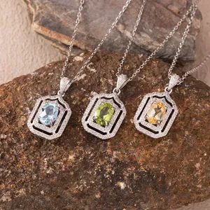 Detailed view of three rectangular silver pendants with oval blue, green, and yellow gemstones