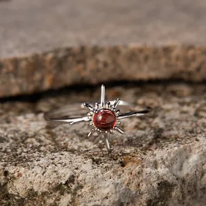 Detail shot of a natural garnet sunburst ring in sterling silver on a stone base