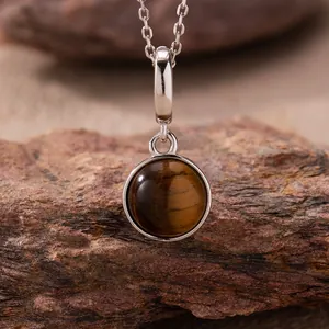 Detailed view of a round polished tiger's eye pendant on a 925 sterling silver necklace chain