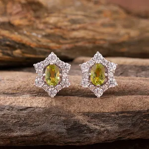 Detailed view of silver sunflower earrings with oval green gemstone and white accents
