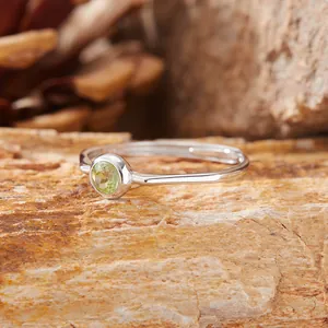 Dettaglio macro di una pietra preziosa verde tonda incastonata in un anello argento S925.