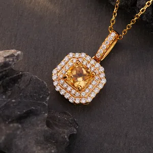 Detailopname van gouden citrien hanger met dubbele halo van kristallen op donkere steen