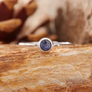 Dettaglio di uno zaffiro blu tondo incastonato in un anello di argento S925 lucido.