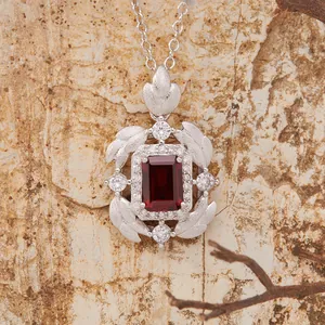 Macro view of S925 silver necklace with emerald-cut red garnet and brushed feather detail