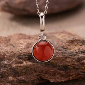 Exquisite close-up of a round red agate pendant necklace resting on a natural rock texture