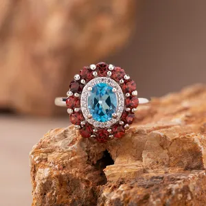 Detailaufnahme eines Silberrings mit blauem Topas und einem Kranz aus roten Granaten.