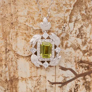 Detailed macro shot of S925 sterling silver feather pendant with emerald cut green gemstone