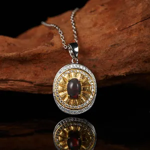 Close-up detail of vintage S925 silver necklace with oval garnet pendant and gold sunburst.