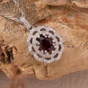 Close-up of a vintage red oval gemstone pendant featuring double halo micro-pave crystals