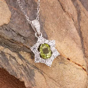 Macro detail of a sunflower-shaped s925 silver pendant with an oval natural green gemstone