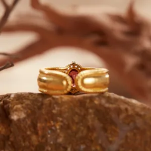 Dettaglio macro di un anello vintage in argento S925 con granato e finitura oro spazzolato