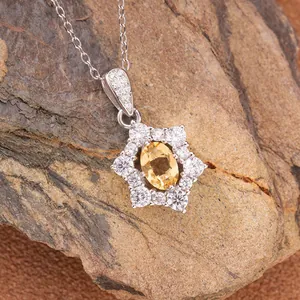 Close-up of S925 silver sunflower pendant with yellow gemstone on natural rock background.