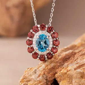 Detaillierte Makroansicht des ovalen blauen Topas-Anhängers mit rotem Granat-Heiligenschein