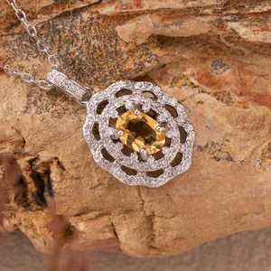Close-up detail of a silver pendant with yellow citrine and white crystals on rock