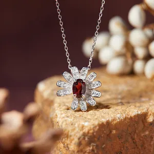 Macro shot of a silver daisy necklace featuring an oval red gemstone and clear crystals.