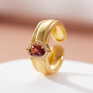 Primo piano di anello vintage in argento S925 con granato rosso e finitura dorata spazzolata