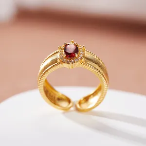 Primo piano di anello rétro in argento S925 con granato naturale e finitura oro spazzolato.