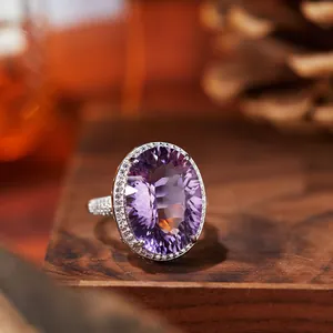 Macro view of large oval amethyst silver ring with halo diamond accents on wood