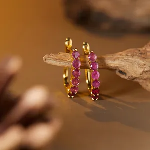 Detailed macro view of S925 gold-plated silver hoop earrings set with tiny pink rubies