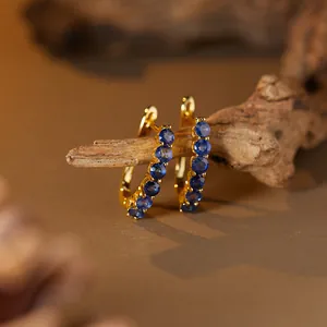 Close-up detail of gold-plated silver hoop earrings with micro-pave blue sapphires
