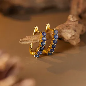 Detail view of gold S925 silver hoop earrings with micro-pave blue sapphire stones.