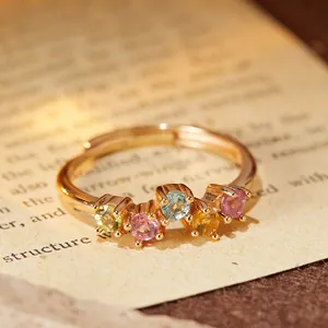 Dettaglio macro di un anello regolabile dorato con cinque vivaci pietre preziose multicolori