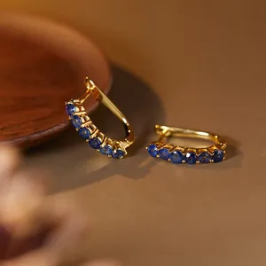 Detailed view of gold S925 silver hoop earrings featuring micro-pave blue sapphires.