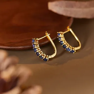 Close-up detail of luxury S925 silver gold-plated hoop earrings with micro-set blue sapphires