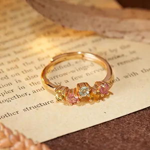 Primo piano dettagliato di un anello in tormalina con cinque gemme colorate su carta