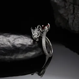 Primo piano di un anello a forma di drago in argento con una pietra di granato rosso.