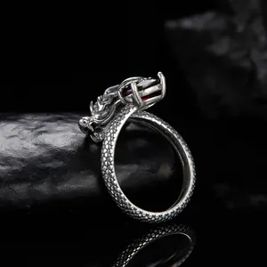Vista macro di anello dragone in argento S925 con granato e trama a scaglie fitte