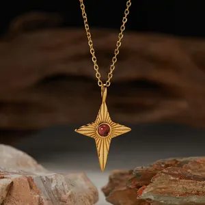 Close-up of a gold-plated star pendant necklace featuring a central red garnet gemstone.
