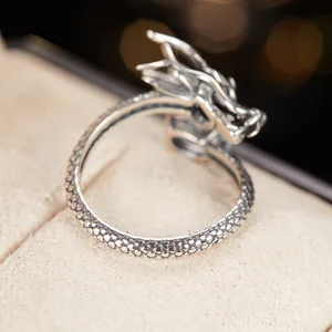 Primo piano dettagliato della trama a squame e della testa di un anello a forma di drago in argento
