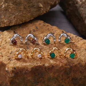 Macro shot of textured silver earrings with natural pearls and agate beads on rocks.