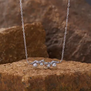 Macro view of a delicate S925 sterling silver necklace featuring pearls on a rocky backdrop
