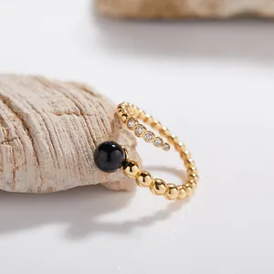 Primer plano de anillo de plata S925 bañado en oro con ágata negra y piedras brillantes.