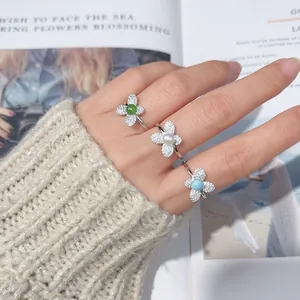 Detailed view of three floral silver rings with pearl and gemstones worn on a hand