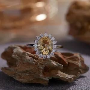 Vue détaillée d'une élégante bague en argent avec pierre jaune ovale et halo