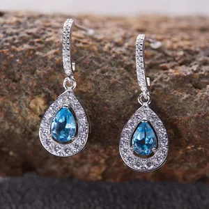 Primo piano di orecchini a goccia in argento S925 con topazio blu e pietre halo