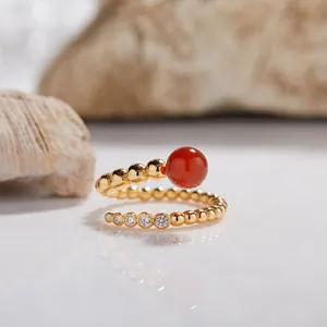 Primer plano de anillo en espiral de plata S925 dorada con ágata roja y circonitas